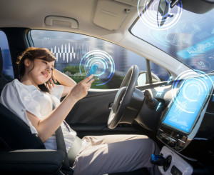 Une jeune femme assise au volant d'une voiture autonome regarde l'écran de son smartphone