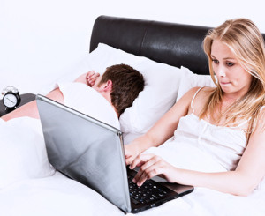 Frau liegt mit Laptop im Bett