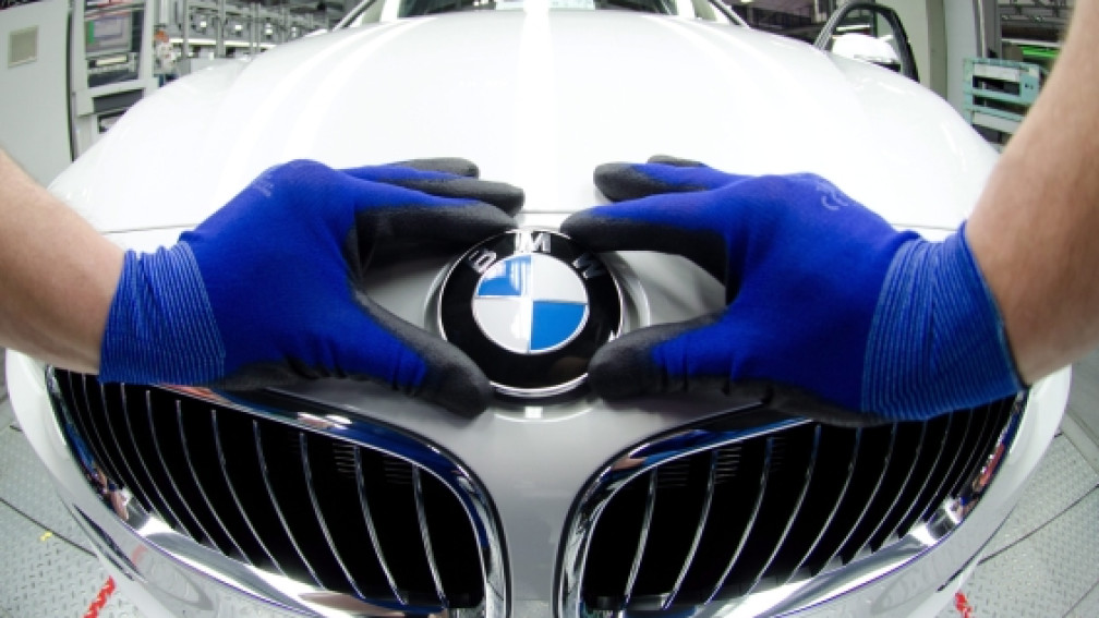 Hände umschliessen BMW-Symbol auf Auto