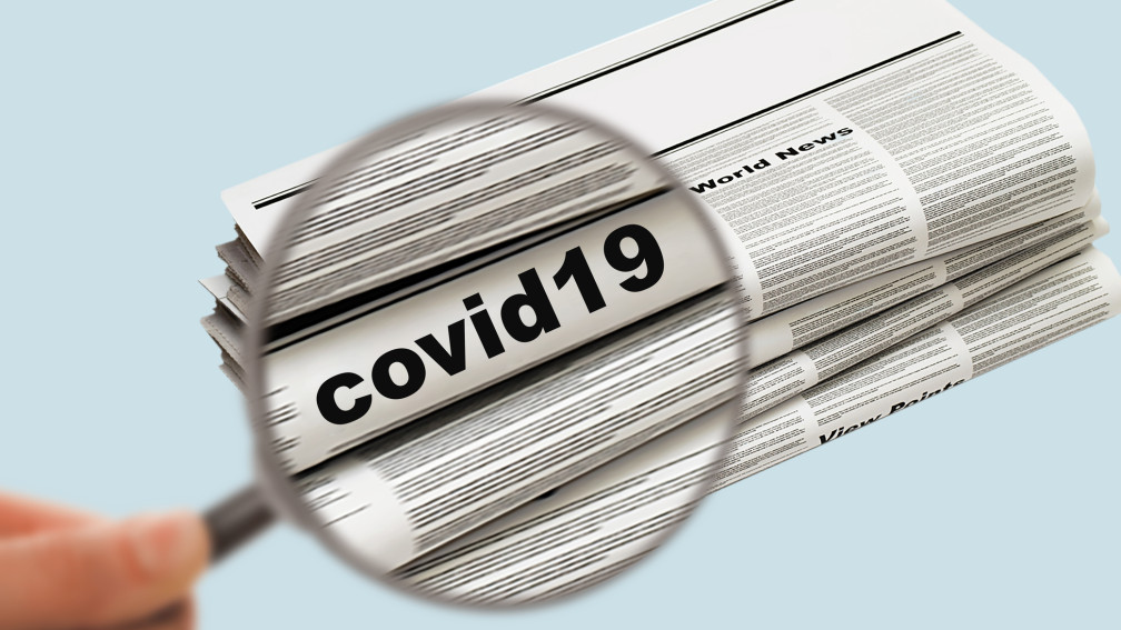 Lupe vergrössert das Wort "covid-19" auf einer Zeitung