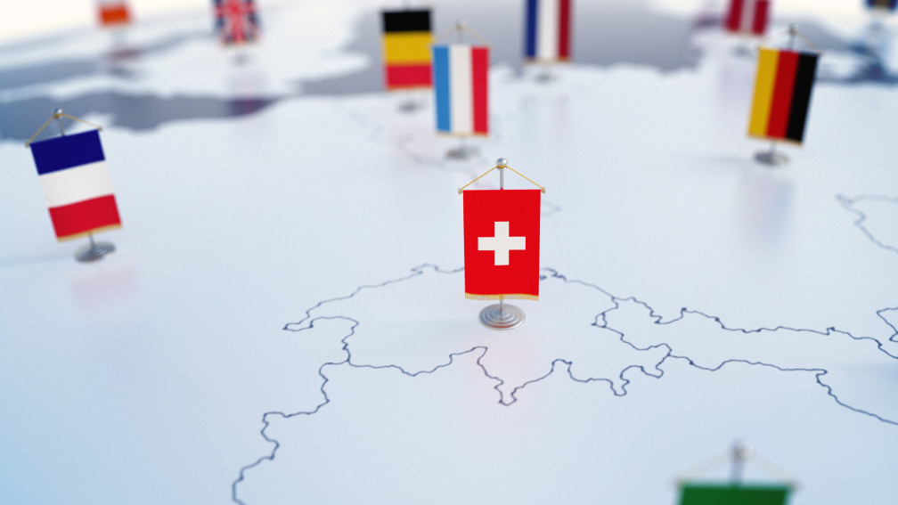 Schweizer Flagge auf Europakarte im Fokus. Unscharf die Flaggen der anderen Länder