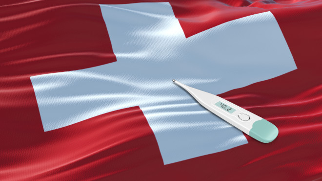 Fiebermesser mit hoher Temperatur liegt auf Schweizer Flagge
