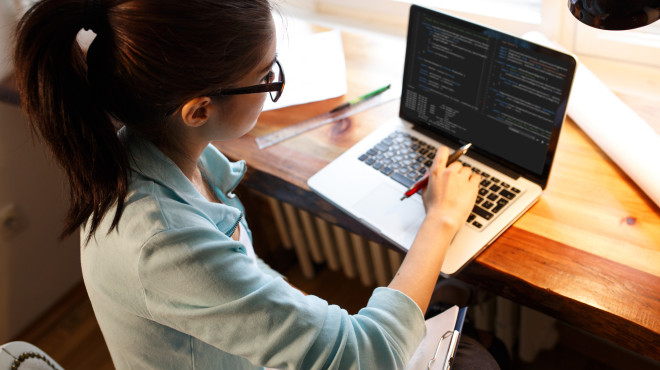 Junge Frau beim Programmieren auf dem Laptop