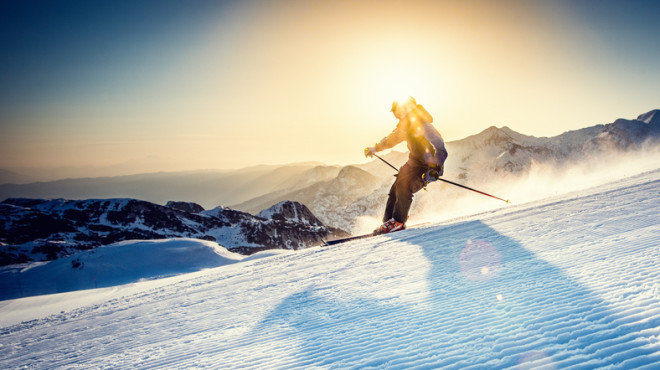 Skifahrer mit Sonne im Hintergrund
