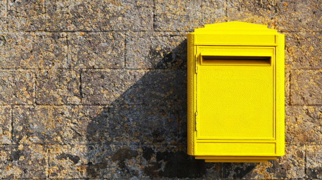 Gelber Postkasten an einer Wand