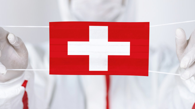 Arzt hält Atemmastke mit Schweizerkreuz