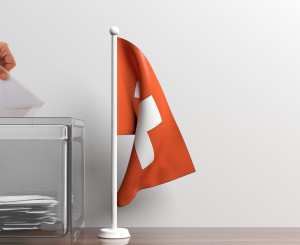Wahlurne und eine Schweizer Flagge daneben