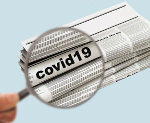 Lupe vergrössert das Wort "covid-19" auf einer Zeitung