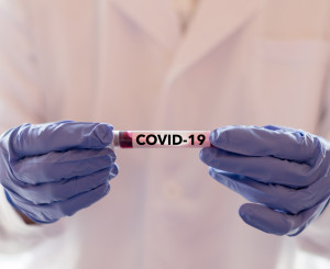 Doctor holding a vial that says "covid 19)