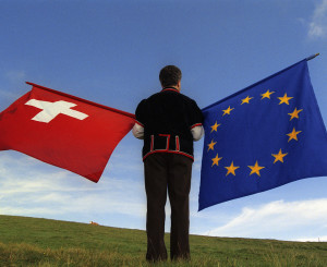 Un homme de dos tient un drapeau suisse et un drapeau européen