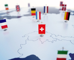 Schweizer Flagge auf Europakarte im Fokus. Unscharf die Flaggen der anderen Länder